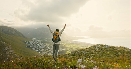 Image showing Woman, hiking on mountain top and freedom or success of travel goals, trekking adventure and nature. Back of hiker or winner in backpack and arms up, celebration or achievement on cliff and cityscape