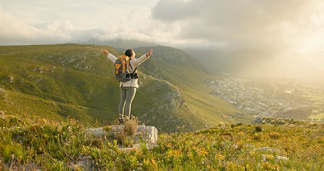 Image showing Woman, mountain top and freedom, hiking goals, celebration or travel achievement in nature adventure. Person or winner in backpack with arms up for trekking success, energy and yes on a cliff or rock