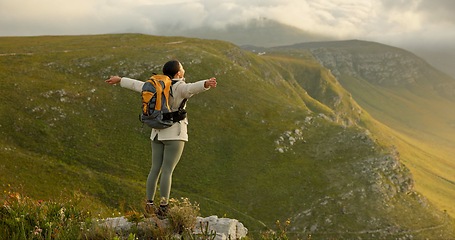 Image showing Woman, mountain top and freedom, trekking goals, celebration or travel achievement in nature adventure. Person or winner in backpack with arms up for hiking success, energy and yes on a cliff or rock