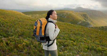 Image showing Woman, hiking on mountains and breathing fresh air for outdoor wellness, fitness and health in nature. Happy young person in wind with backpack and trekking on a hill for adventure, travel or journey