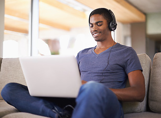 Image showing Man, face and music with laptop on couch for internet streaming, podcast and online research with smile. Student, black person and technology with headphones for relax, studying and learning in home