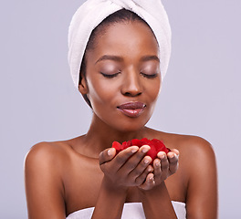 Image showing Towel, skincare and black woman with red petals, beauty and dermatology on a white studio background. Happy, African person and model with natural cosmetics and grooming with treatment and luxury