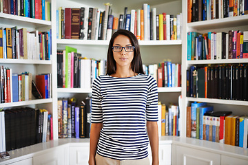 Image showing Woman, portrait and serious by bookshelf in home with books for reading, learning and knowledge in living room. Person, face and confident by house library with magazine, journal and study collection