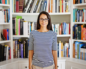 Image showing Woman, portrait and happy by bookshelf in home with books for reading, learning and knowledge in living room. Professor, face and smile by library in house with magazine, journal and study collection