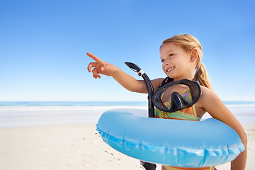 Image showing Girl, smile and goggles for swimming at beach, pointing and equipment for water on holiday. Female person, child and happy on tropical vacation in outdoors, inflatable and blue sky for mockup space