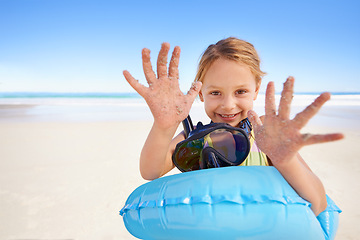 Image showing Girl, portrait and hands for swimming on sand, beach and goggles or inflatable donut on holiday. Female person, child and happy on tropical vacation in outdoors, ocean and blue sky for mockup space