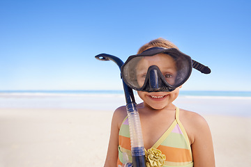 Image showing Girl, portrait and goggles for snorkeling at beach, smile and equipment for swimming on holiday. Female person, child and travel on tropical vacation in outdoors, sand and blue sky for mockup space