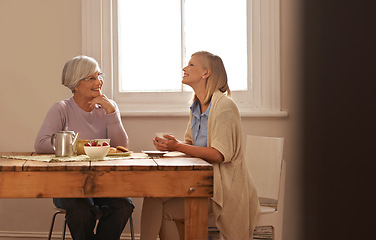 Image showing Family, happy woman and senior mother drinking coffee at breakfast, bonding and smile. Elderly mom, adult and tea cup at table for conversation, love and daughter eating cookies at home together