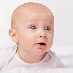 Image showing Newborn, baby and blue eyes with laying on bed for curiosity, development and growth in bedroom at house. Adorable, child and cute infant with vest in home to relax, observe and wonder for knowledge