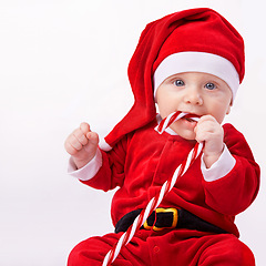 Image showing Baby, portrait and studio with santa costume for first Christmas holiday, candy cane and white background. Boy toddler, xmas and outfit for festive season or celebration, innocent and adorable in hat