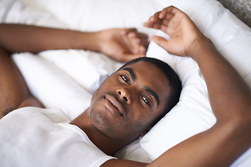 Image showing Black man, portrait and morning with bed in relax for wakeup, comfort or resting on duvet or sheets at home. Face of African male person lying awake in bedroom with pajamas for weekend at the house