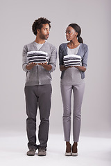 Image showing Couple, laundry and teamwork in studio for helping, support and domestic chores on a white background. Serious African man and young woman with clothes in hands for fashion, neat and gender equality