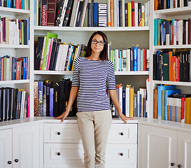 Image showing Woman, portrait and smile by bookshelf in house with books for reading, learning and knowledge in living room. Professor, face and happy by home library with magazine, journal and study collection