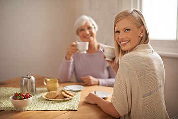 Image showing Portrait, happy woman and senior mother drinking coffee at breakfast, bonding and smile in house. Face, elderly mom and adult with tea cup at table, food and family eating cookies at home together