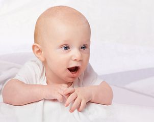 Image showing Cute baby, child and shocked on bed for curiosity, reaction and surprise with laying in nursery at house. Adorable, kid and excited infant in home to relax, observe or wonder for development