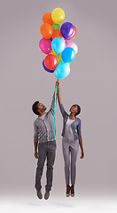 Image showing Couple, float and flying with bunch of balloons for event, birthday or romance on a gray studio background. Man and woman holding colorful blowups of helium up for date or anniversary on mockup space