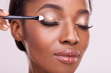 Image showing Black woman, face and brush for eyeshadow with makeup, beauty and lashes isolated on pink background. Skin glow, cosmetics product and tools for cosmetology, shimmer or glitter with shine in studio