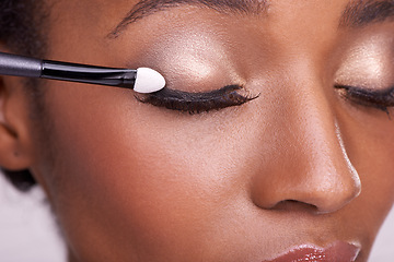 Image showing Black woman, closeup of face and brush for eyeshadow with makeup, beauty and lashes on pink background. Skin glow, cosmetics product and tools for cosmetology, shimmer or glitter with shine in studio