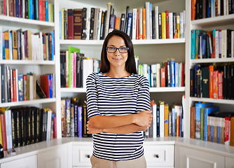 Image showing Woman, portrait and confidence by bookshelf in home with books for reading, learning and knowledge in living room. Professor, face or happy by house library with magazine, journal or study collection