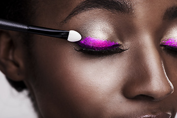 Image showing Closeup of black woman, lashes and brush for eyeshadow with makeup, beauty and color on pink background. Skin glow, cosmetic product and tools for cosmetology, shimmer or glitter with shine in studio