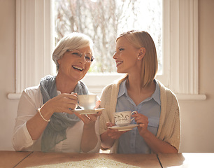 Image showing Family, happy woman and senior mother drinking tea at breakfast, bonding and smile in house. Laughing, elderly mom and daughter with coffee cup at table, conversation or funny people at home together