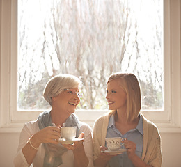 Image showing Family, happy woman and senior mother drinking coffee at breakfast, talking and smile. Laughing, elderly mom and daughter with tea cup, conversation and listening to funny story at home together