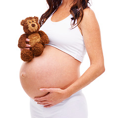 Image showing Woman, pregnant and teddy bear in studio with hand on stomach for care, support or love for future child. Mother, belly and protection of baby with abdomen, wellness and maternity on white background