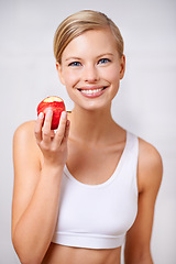 Image showing Portrait, woman and smile in studio with apple, nutrition and diet for health and wellness. Female person, fruit and workout for fitness or weight loss, wellbeing and happiness on white background