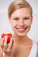 Image showing Happy woman, portrait and nutrition with apple in food, health and wellness on a gray studio background. Face of female person with smile and natural organic red fruit for vitamins, fiber or snack
