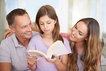 Image showing Father, girl and mom with book on sofa for hug, care or connection in family home for reading. Dad, mother and daughter on couch together with teaching, education or embrace for storytelling in house