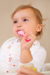 Image showing Baby girl, spoon and eating for nutrition, food and development with enjoyment at house, living room and home. Female child, infant and kid happy for feeding, breakfast and snack for growth