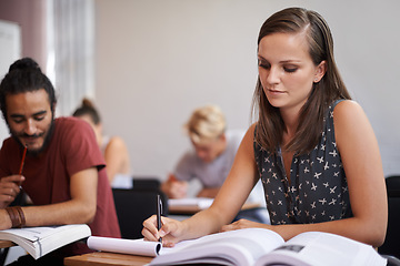 Image showing Woman, student and writing in classroom for studying, reading or summary in book at university. Female person or academic writer taking notes for assignment, test or literature exam on desk at campus