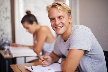 Image showing Happy man, portrait and student with book in classroom for studying, reading or writing summary at university. Male person or academic writer with smile for assignment, test or exam on desk at campus