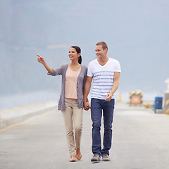 Image showing Couple, ocean and happy in boardwalk on vacation for honeymoon, love and relax in New Zealand. Pointing, relationship and beach for travel on holiday with trip for support, bonding and holding hands