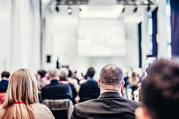 Image showing Speaker giving a talk in conference hall at business event. Rear view of unrecognizable people in audience at the conference hall. Business and entrepreneurship concept.