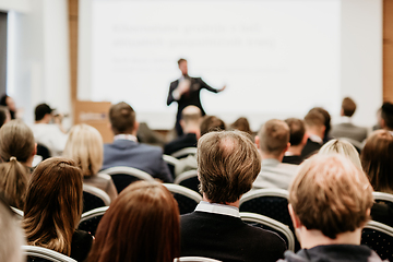 Image showing Speaker giving a talk in conference hall at business event. Rear view of unrecognizable people in audience at the conference hall. Business and entrepreneurship concept.