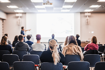 Image showing Speaker giving a talk in conference hall at business event. Rear view of unrecognizable people in audience at the conference hall. Business and entrepreneurship concept.