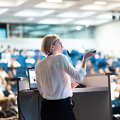 Image showing Female speaker giving a talk on corporate business conference. Unrecognizable people in audience at conference hall. Business and Entrepreneurship event.