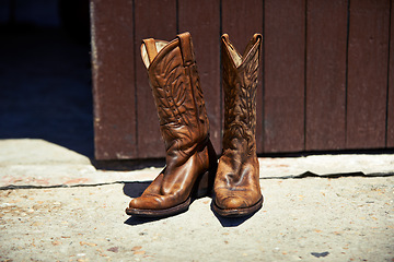 Image showing Cowboy boots, ranch and style at farm for walking, safety and retro fashion on floor, ground and barn. Shoes, leather product and vintage heel for steps, outdoor or aesthetic for agriculture in Texas