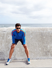 Image showing Man, ocean and stretching for fitness with confidence for workout, health and wellbeing in Chicago. Male person, sportswear and active as runner with exercise at beach and committed with sunglasses.