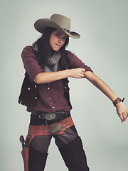 Image showing Tough, woman and cowboy portrait with fashion outfit, in Texas as cowgirl and leather belt. Angry face, rolling up sleeve and ready to fight with gun in holster and comic on a grey background studio