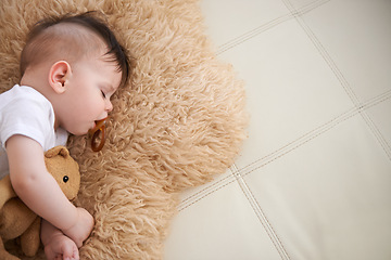 Image showing Baby, sleep and cuddle with teddybear on couch at home, rest and relax with dummy and dream. High angle, toddler, and nap in sofa for child development, growth and innocent with peace for bedtime.