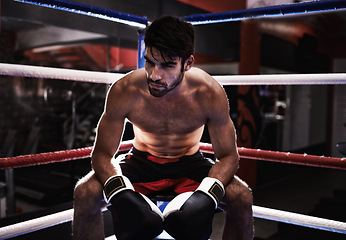 Image showing MMA, boxer and man sitting in ring ready for challenge, competitive and confident from training in gym. Male person, healthy and fitness from practice in exercise studio as athlete and fighter