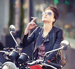 Image showing Woman, leather and cigarette in city with motorcycle for travel, transport or road trip as rebel. Fashion, street and person smoking nicotine with attitude on classic or vintage bike for journey