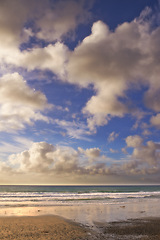 Image showing Beach, landscape and ocean at sand with clouds in blue sky on vacation, holiday or summer in California. Sunset, sea and travel outdoor with calm waves, water and horizon in nature or environment