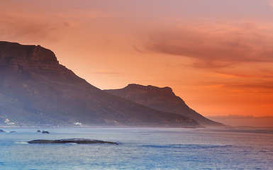 Image showing Ocean, sunset and mountains in nature or sustainable environment and travel destination for vacation. Landscape, sea or sunlight on water on beach, calm or seascape of camps bay for tourist adventure