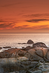 Image showing Ocean, sunset and waves on rocks on tropical island and tourism destination for summer vacation in nature. Sky, clouds and golden color on torrey pines beach, peace and outdoor travel in california