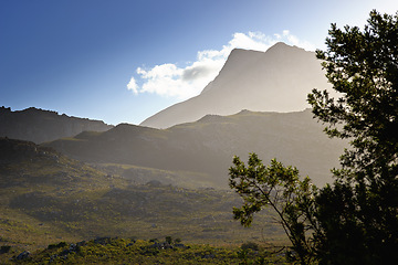 Image showing Mountains, environment and blue sky with summer, clouds and sunshine with landscape and weekend break. Empty, misty and grass with flowers or countryside with growth or travel with vacation or spring