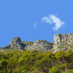 Image showing Mountains, sunshine and blue sky with nature, clouds and stone with landscape and environment. Empty, rock and grass with flowers or countryside with summer and travel with holiday, journey or plants