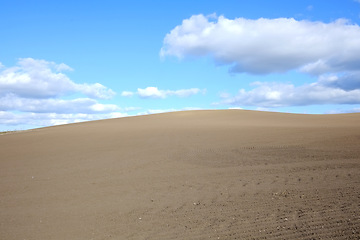 Image showing Desert, landscape and clouds on blue sky background with sand in arid, barren or dry environment. Earth, nature or soil and summer horizon in hot climate or drought with banner, mockup or space